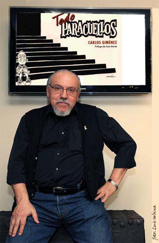 Carlos Giménez junto a una ilustración de su obra más popular.
